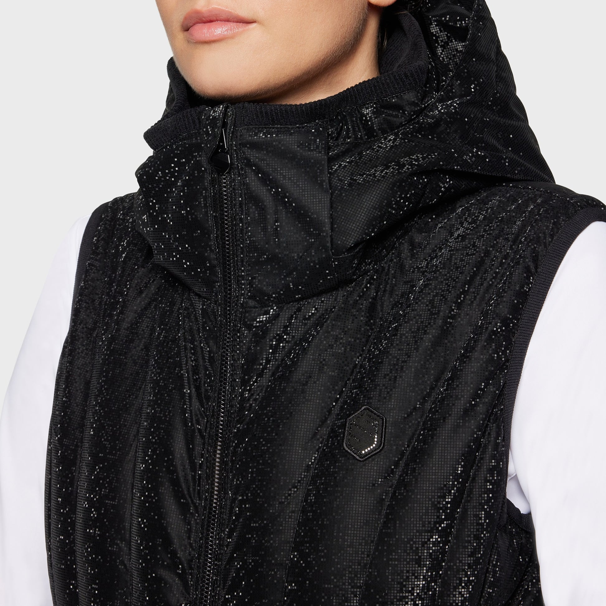 Detail of woman wearing a black quilted vest over a white shirt on a white background