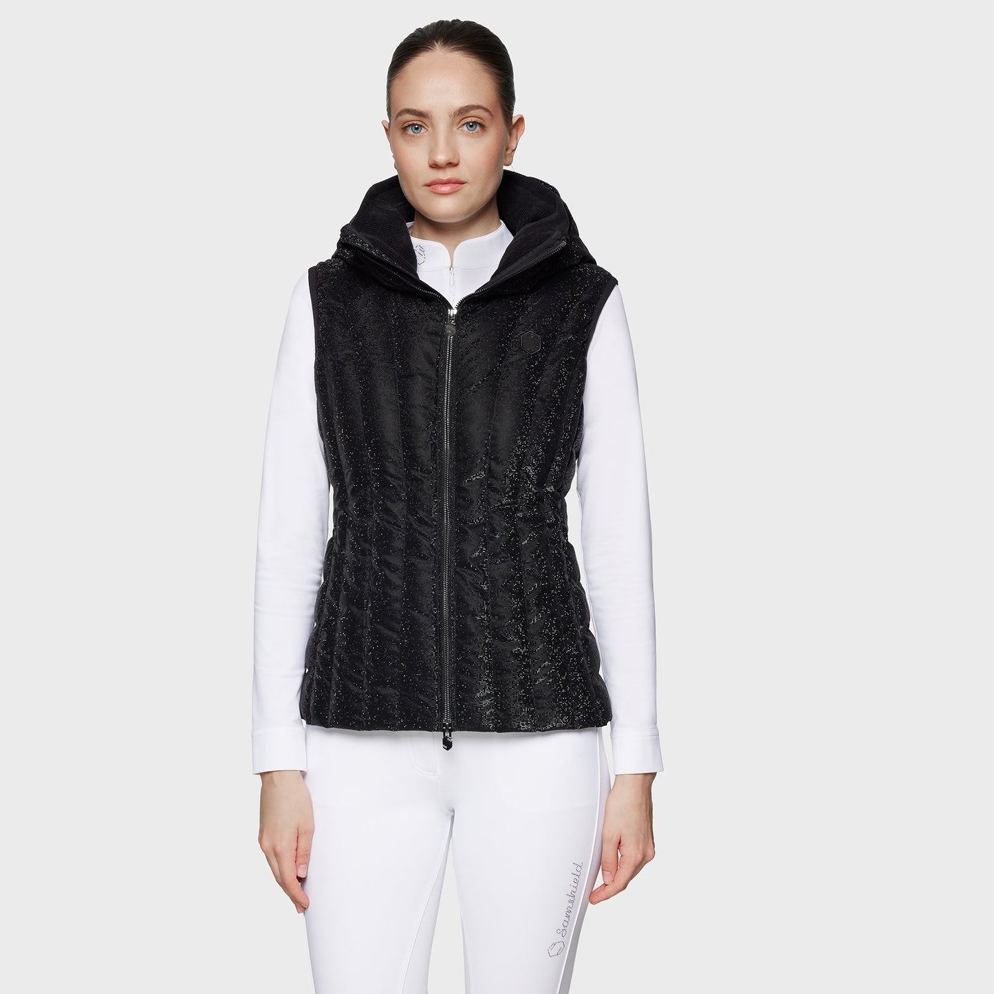 Woman wearing a black quilted vest over a white shirt on a white background