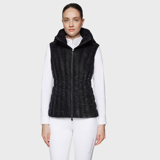 Woman wearing a black quilted vest over a white shirt on a white background