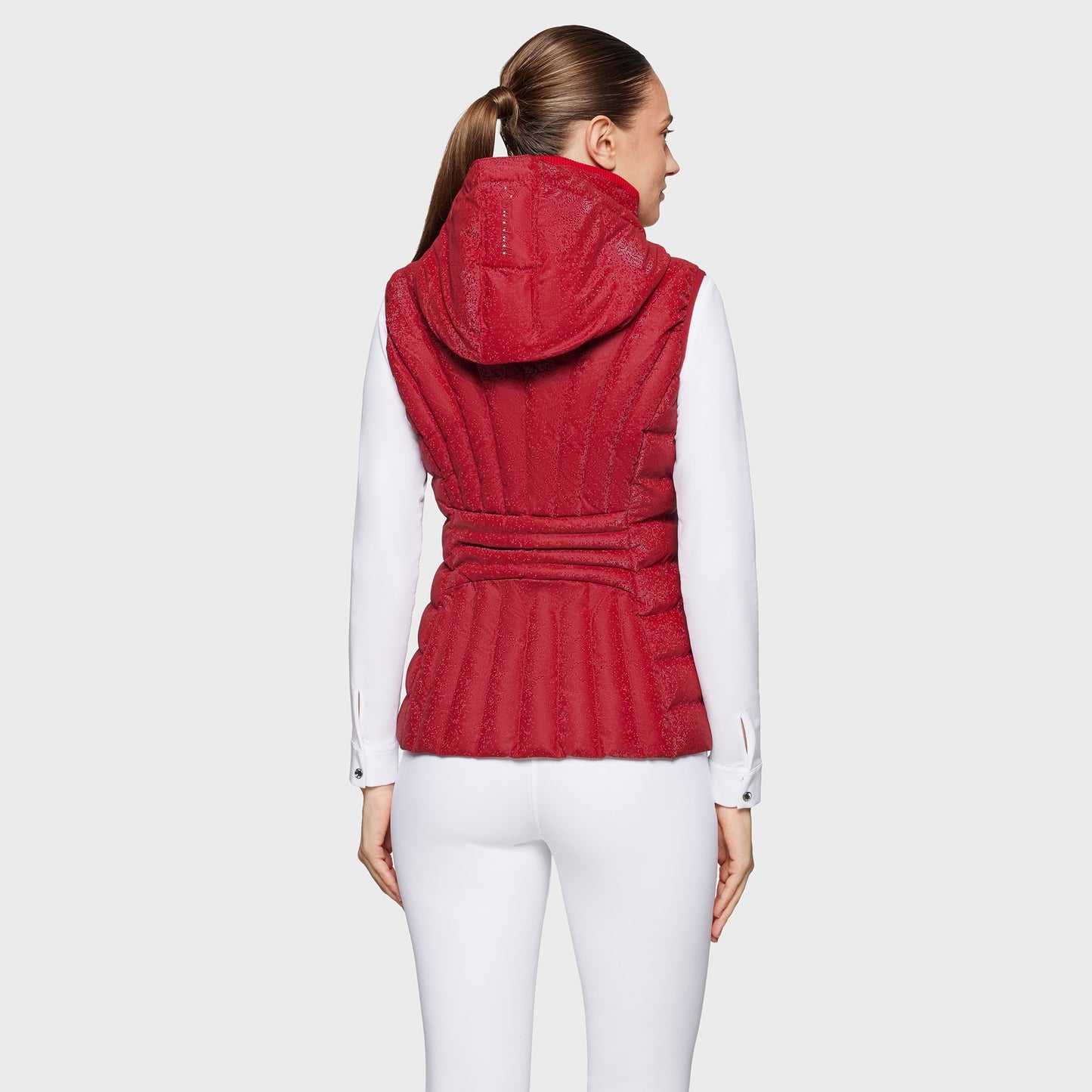 Woman wearing a red quilted vest on a light gray background