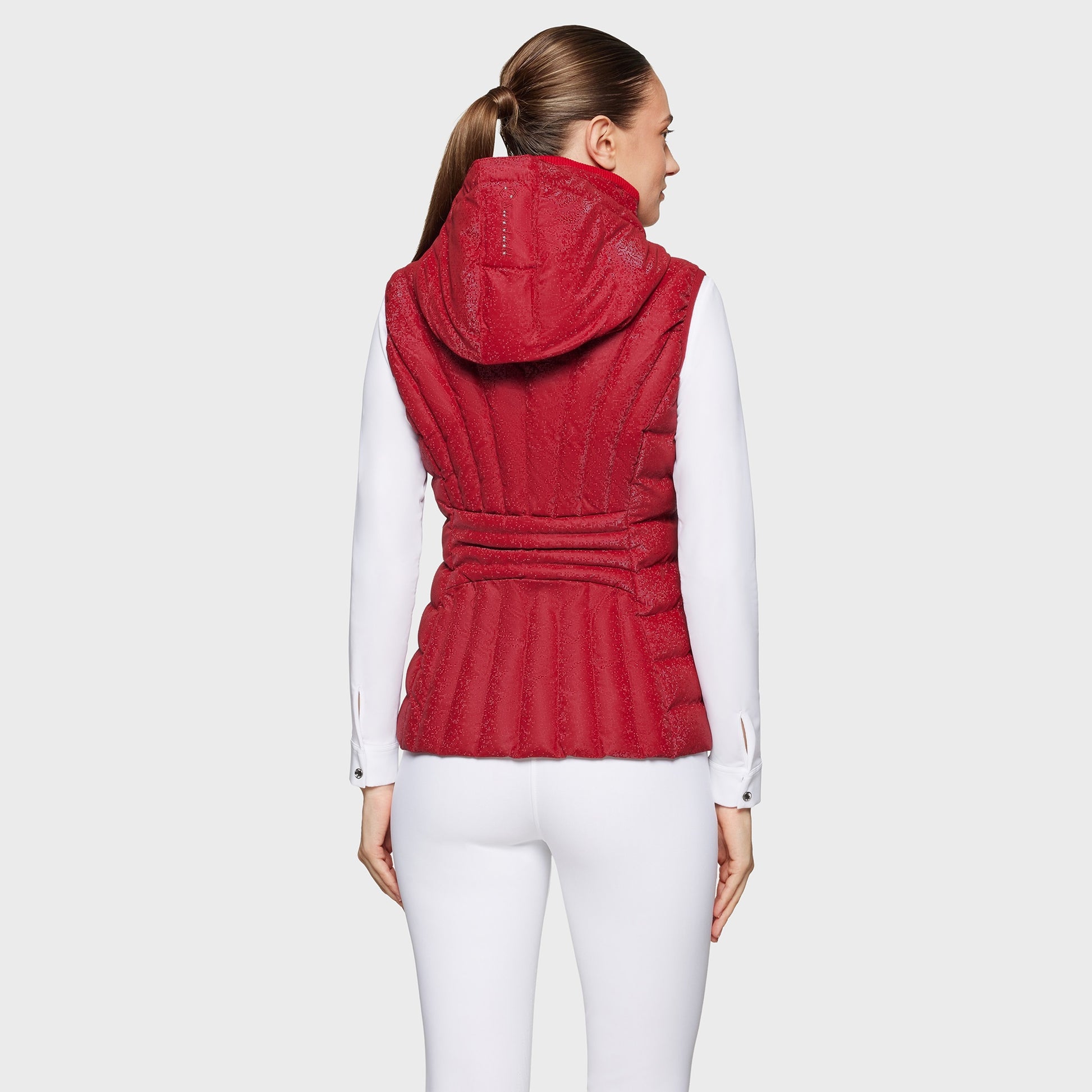 Woman wearing a red quilted vest on a light gray background