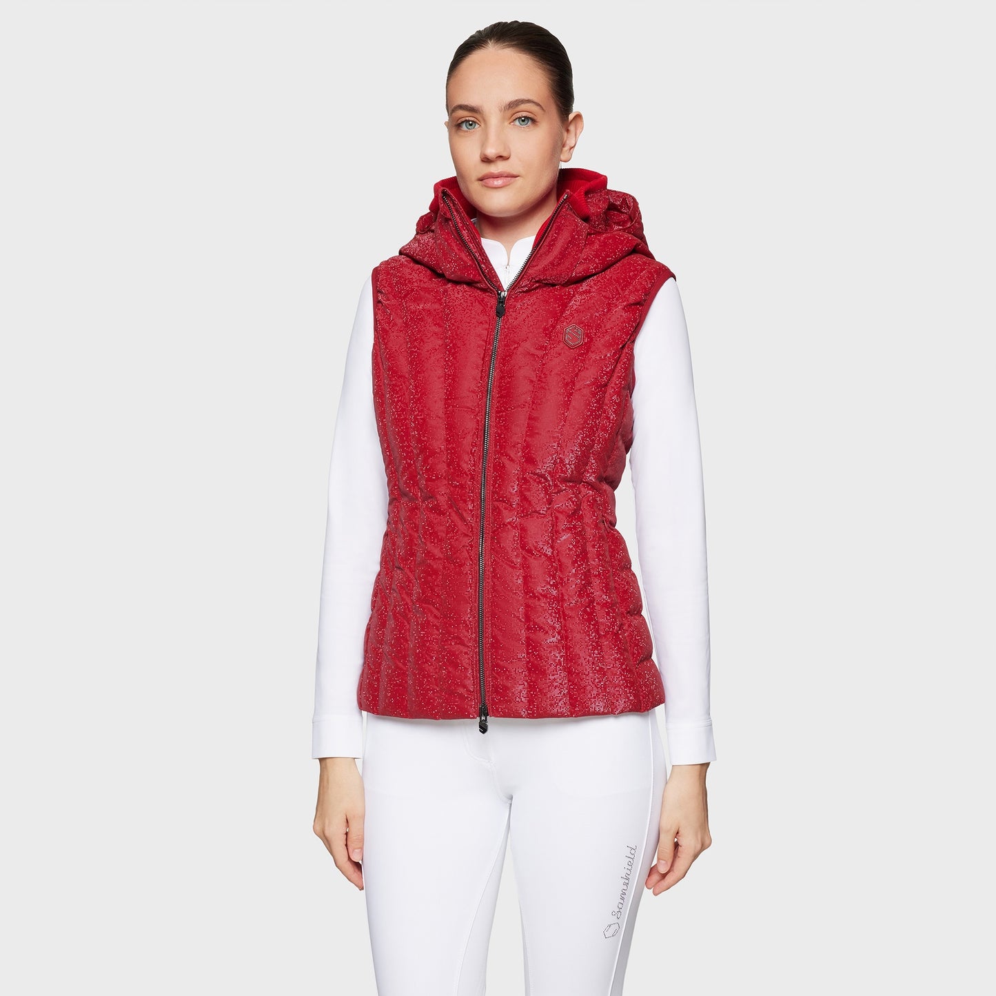 Woman wearing a red puffer vest over a white shirt on a light gray background