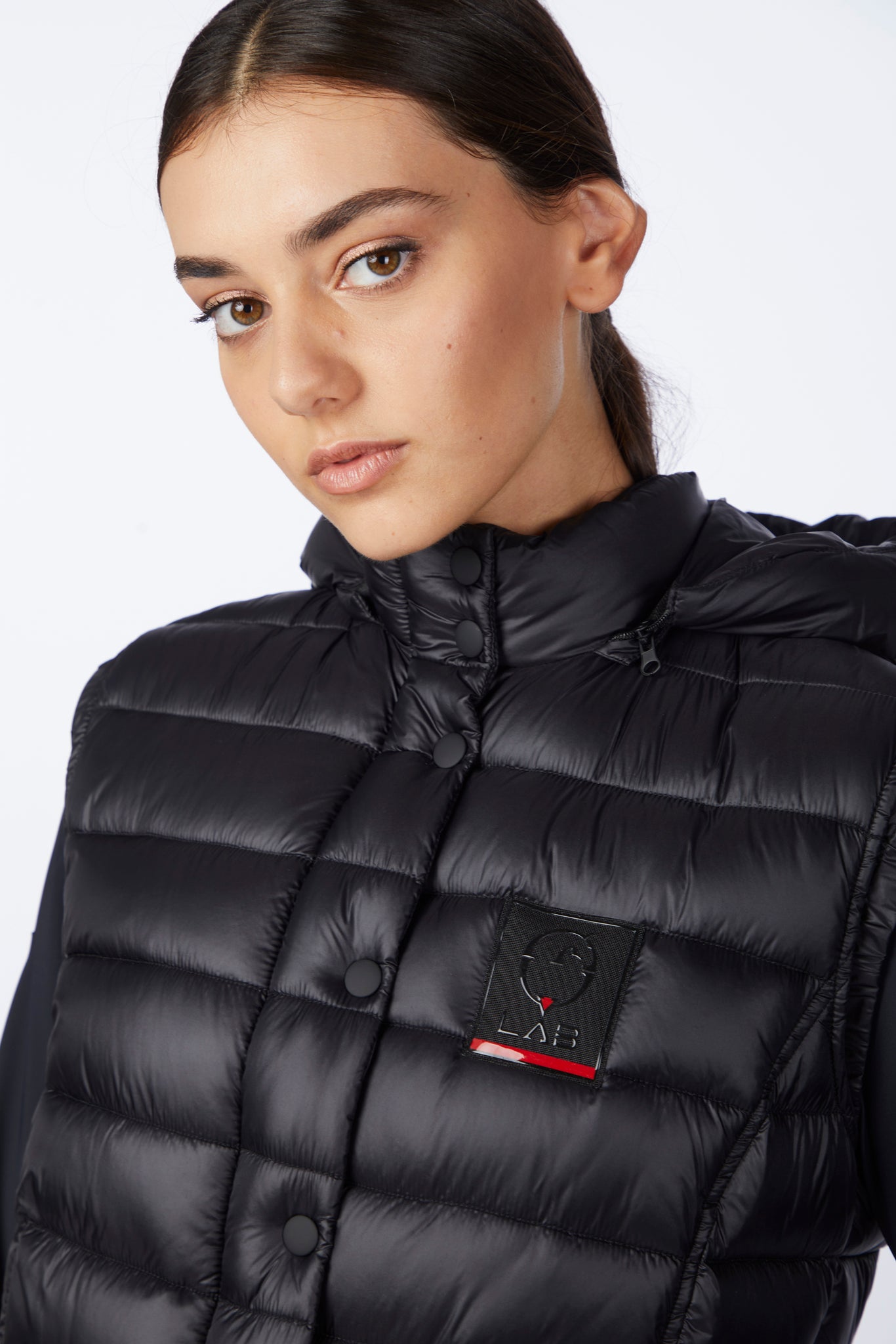 Person wearing a black puffer jacket with a brand logo on a white background