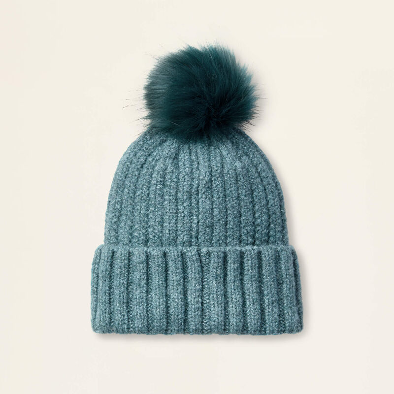 Teal knit beanie with a fur pom-pom on a light beige background