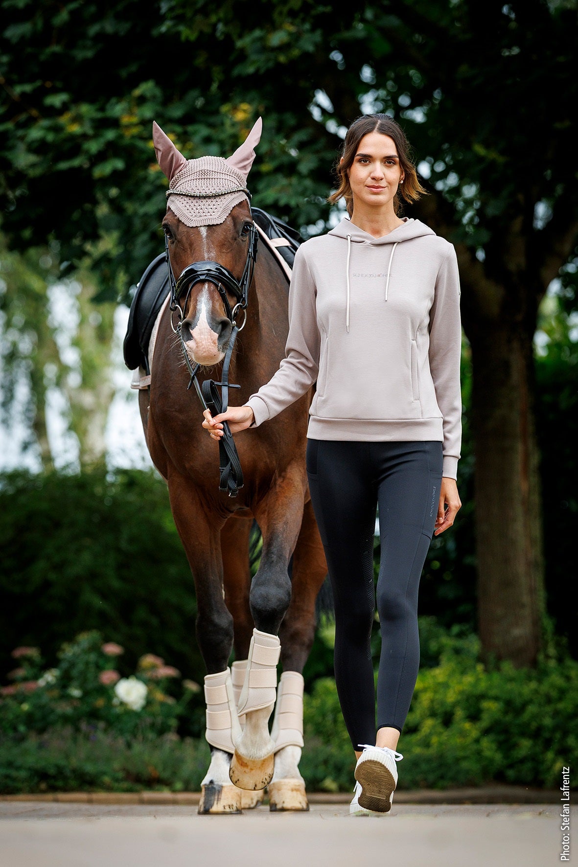 Woman walking with a horse on a path in a park-like setting