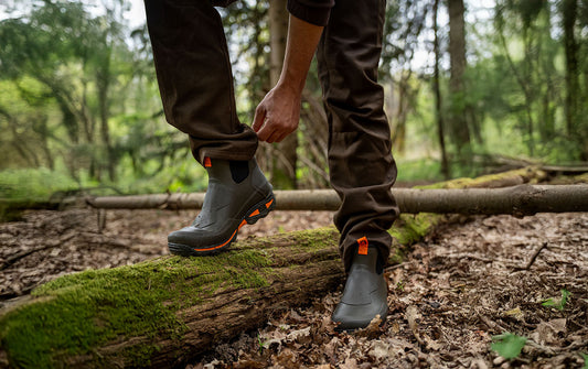 Person wearing a pair of brown ankle boots in a wood setting