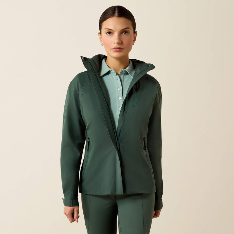 Woman wearing a green jacket over a light blue shirt on a beige background