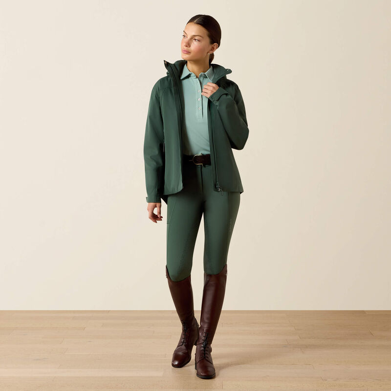 Woman wearing a green equestrian outfit with a beige background