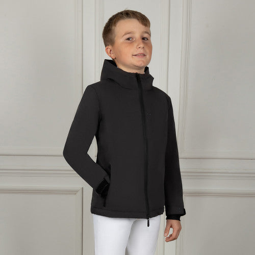 Child wearing a black jacket against a light gray wall