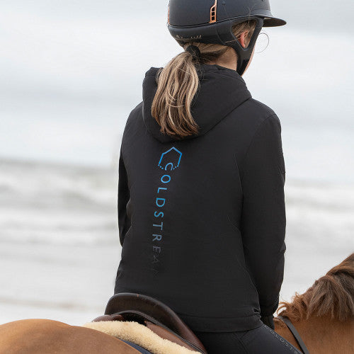 Person wearing a black Coldstream jacket on a horse with a blurred water background