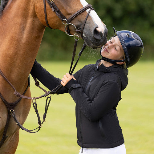 Person in equestrian gear interacting with a horse in a field
