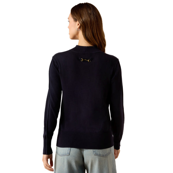 A woman shown from the back wearing a dark navy long-sleeve knit top with a small gold horsebit detail at the base of the neck, paired with light blue jeans against a plain white background.