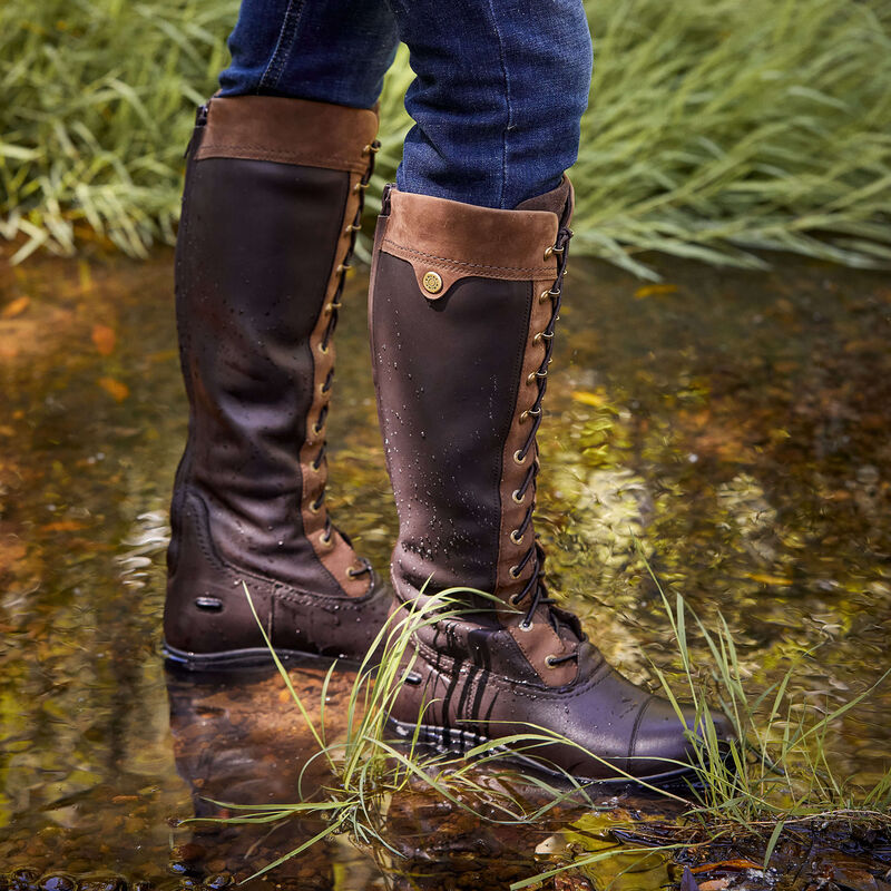 Brown country boot s in a river surrounded by grass