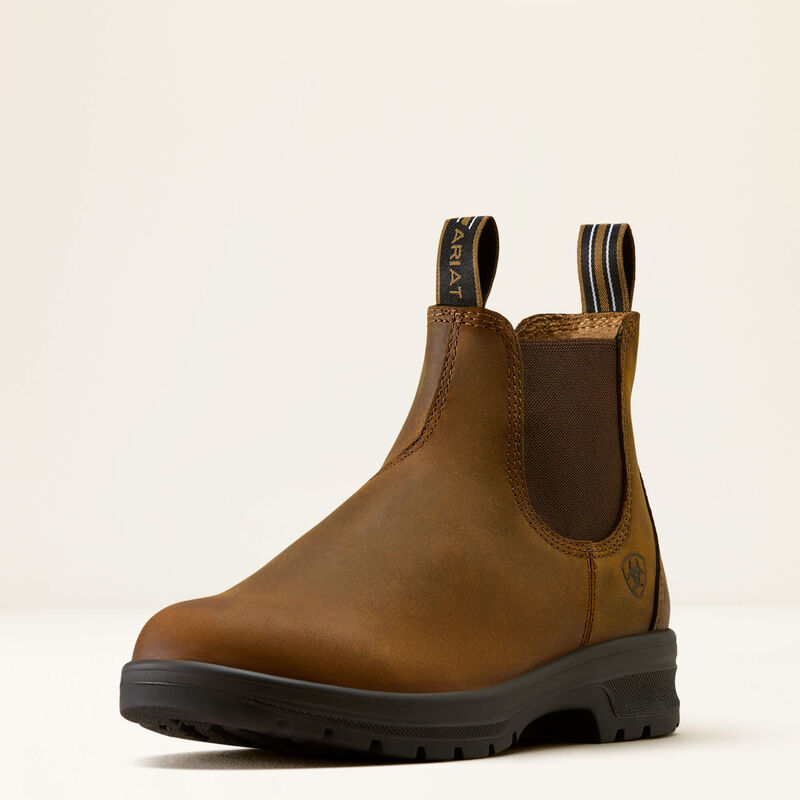 A single brown leather Chelsea-style boot with elastic side gore, pull tabs, and a black lug sole, photographed on a clean off-white studio background.