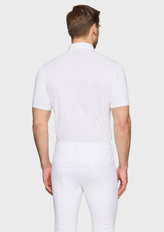 Man wearing a white competition shirt and white breeches on a beige background