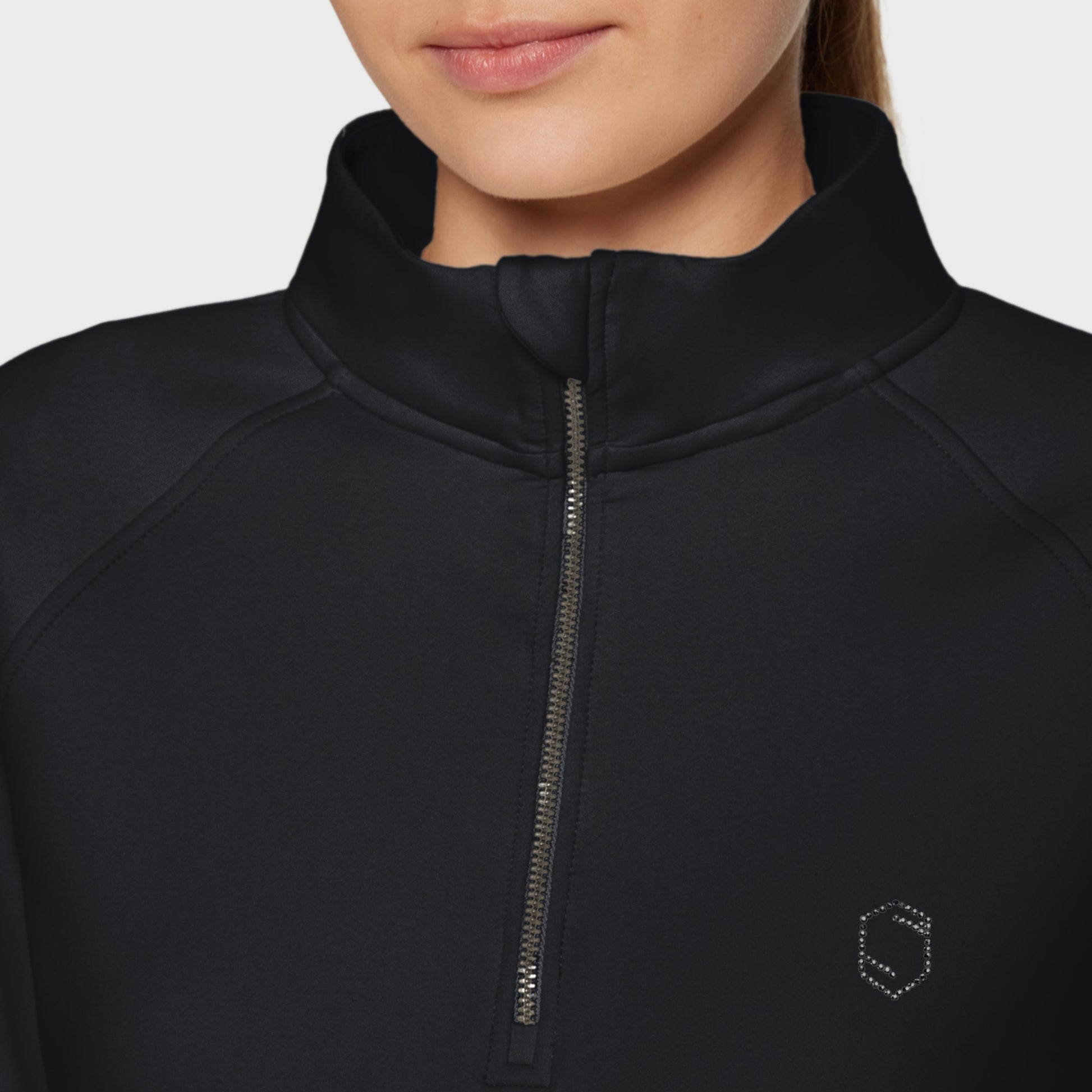Close-up of a black jacket with a zipper and logo on a plain background