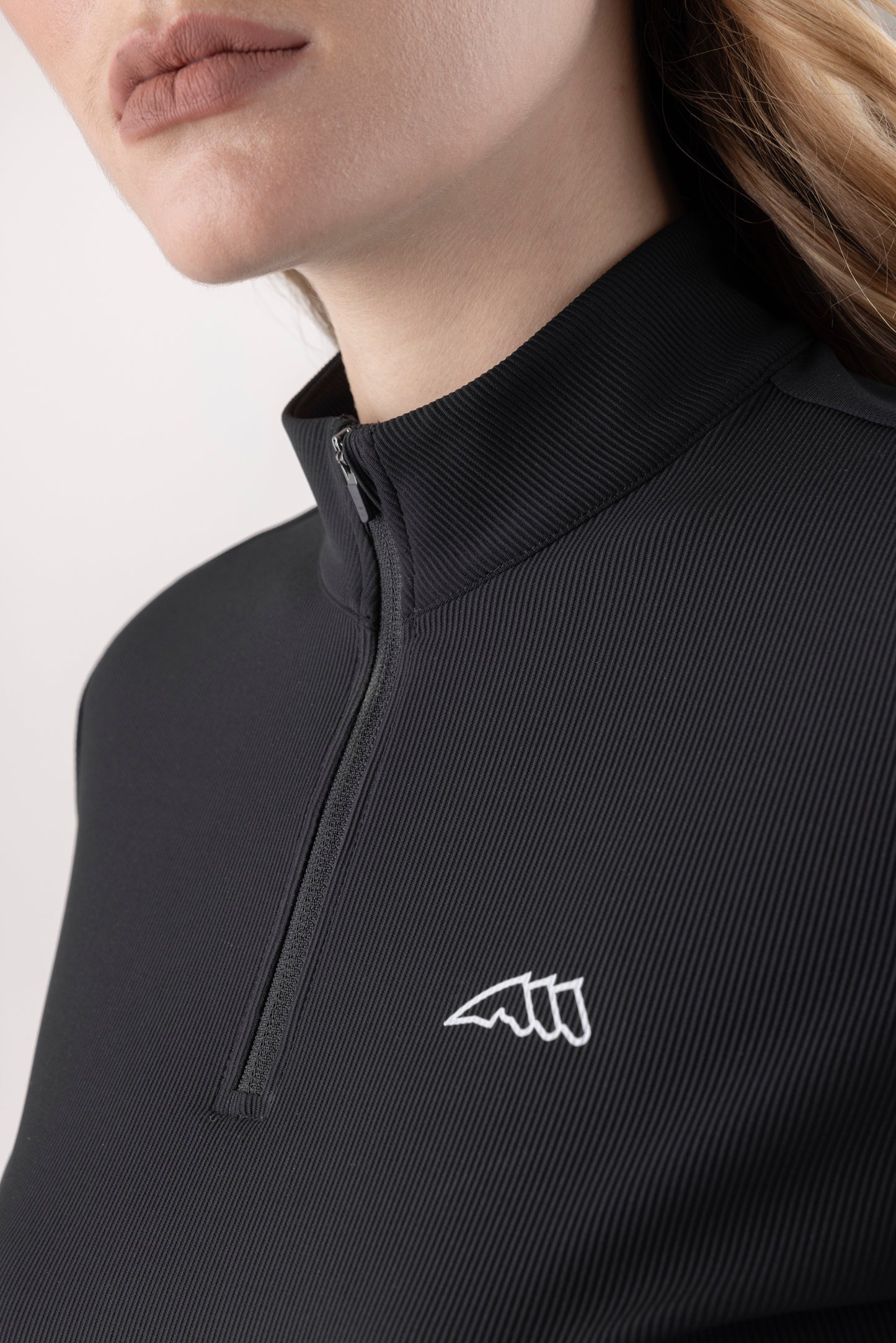 Close-up of a black zip-up garment with a logo on a light background