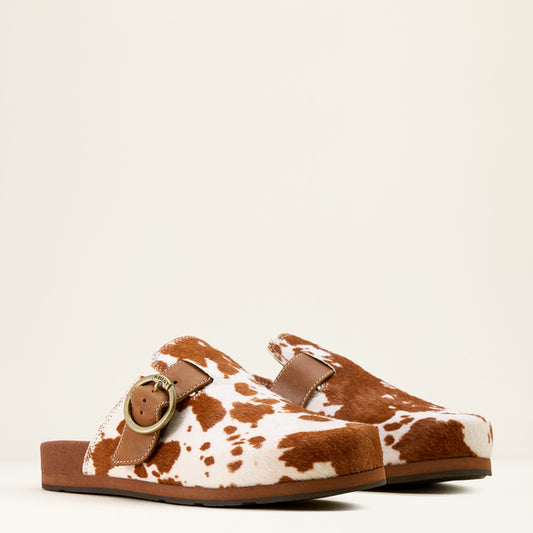Brown and white cow print sandal with a gold buckle on a beige background