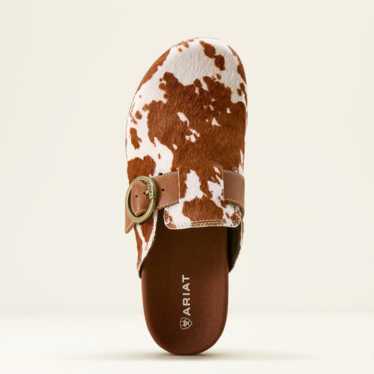 Brown and white cow print sandal with a gold buckle on a beige background