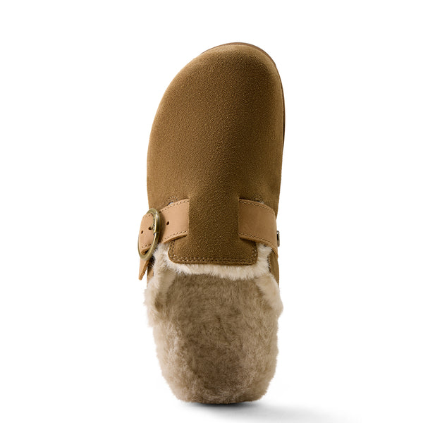 A single brown suede clog-style boot with a tan leather strap and buckle, featuring a fluffy cream shearling lining, shown from a side profile view on a white background.
