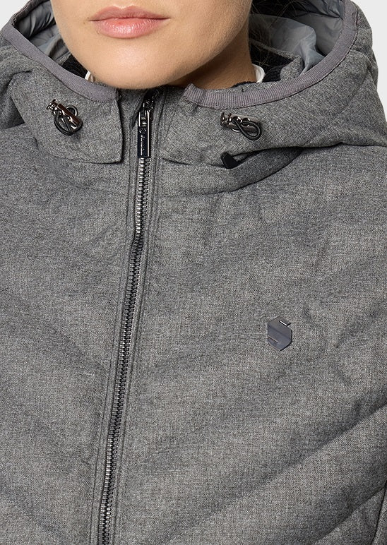 Close-up of a person wearing a heather gray hooded puffer jacket with a front zipper, black zipper pulls, and a small shield-shaped logo on the left chest.