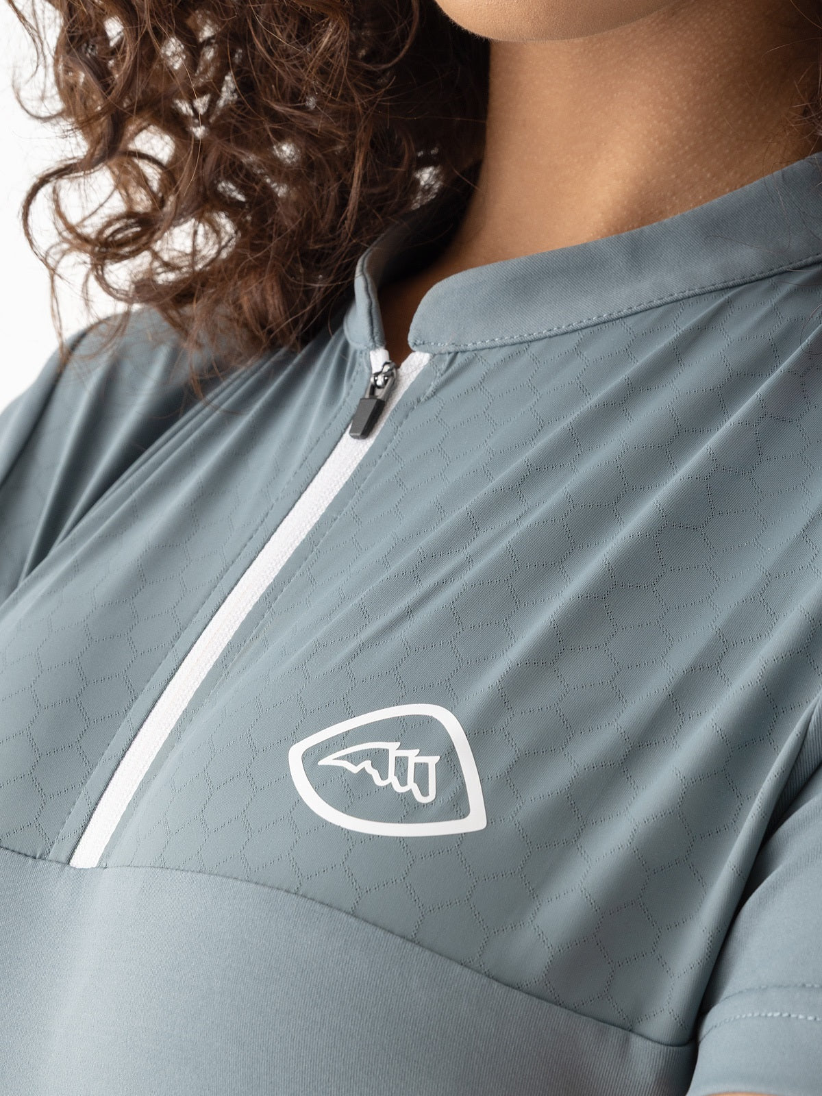 Close-up of a person wearing a gray jacket with a logo on the chest.