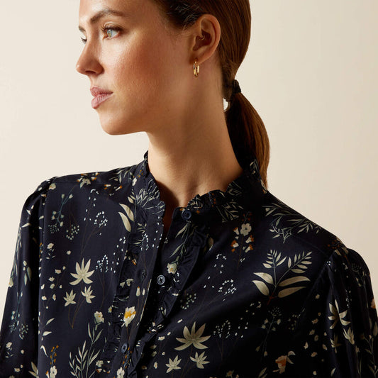 Woman wearing a dark floral blouse against a beige background