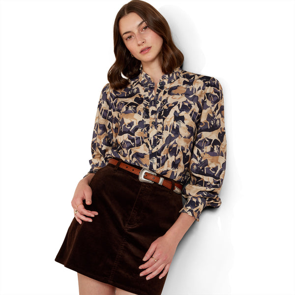 Woman wearing a patterned blouse and brown skirt on a white background