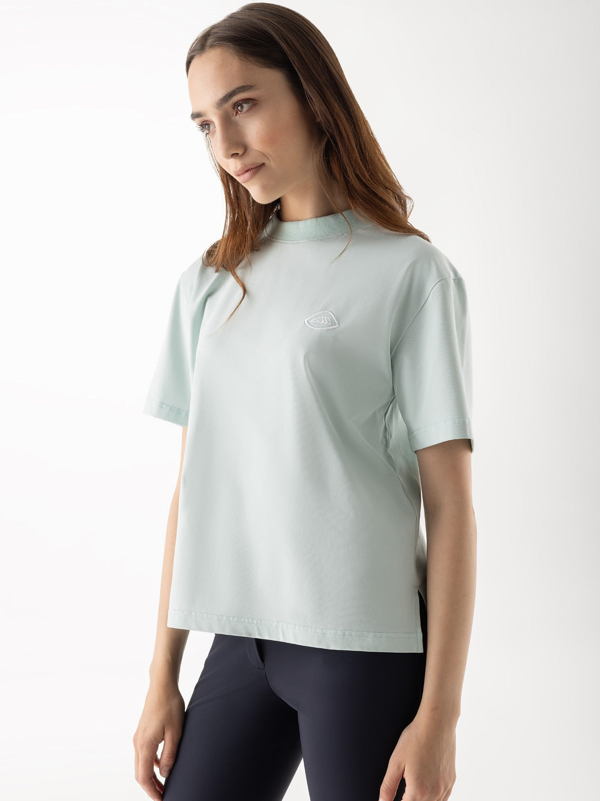 Woman wearing a light green athletic shirt and dark leggings on a white background