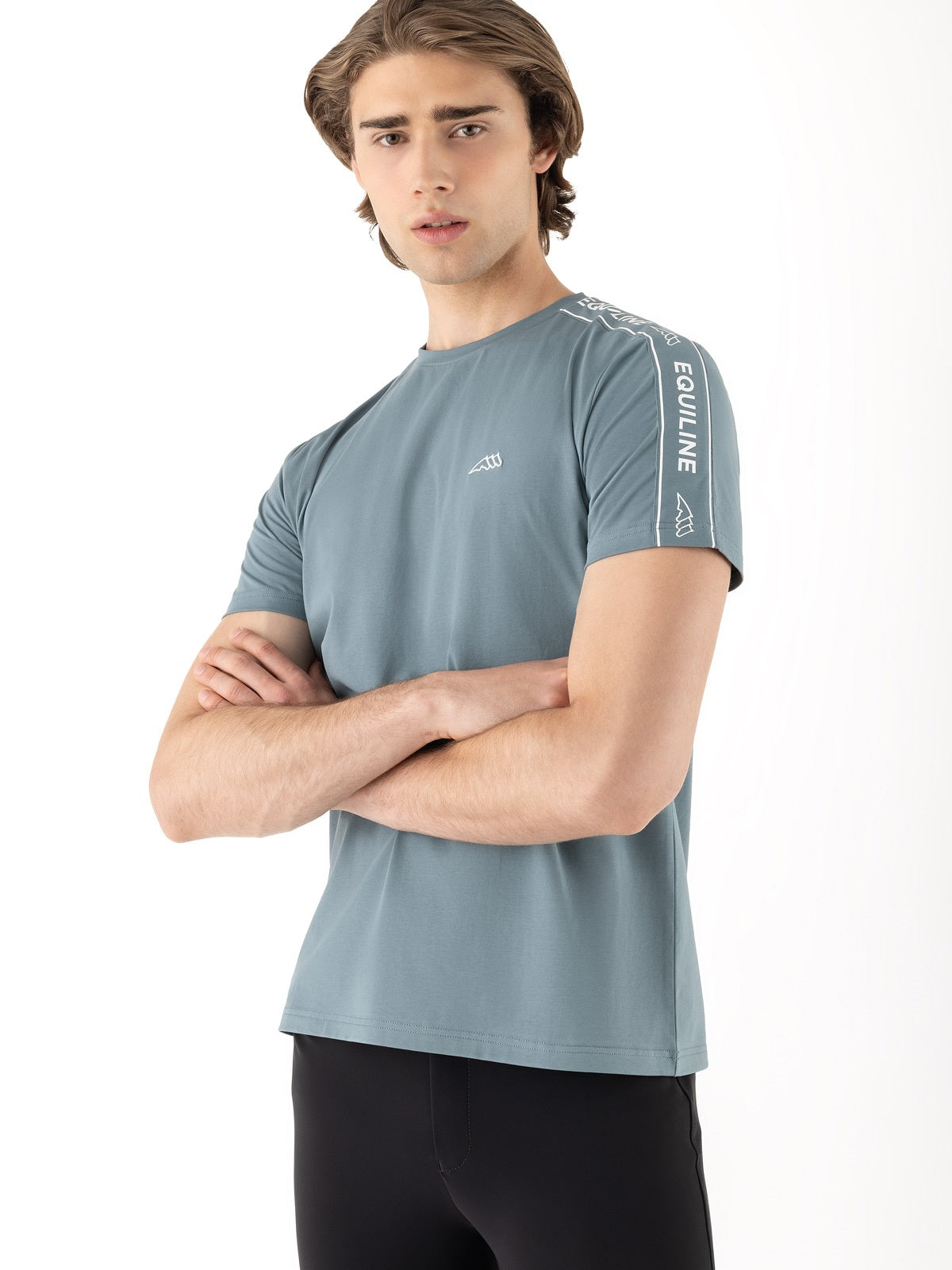 Man wearing a light blue athletic shirt with branding on a white background