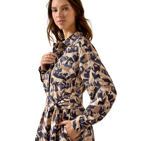 A woman wearing a long-sleeve collared dress with a beige, brown, and navy blue abstract pattern, photographed against a solid white background.
