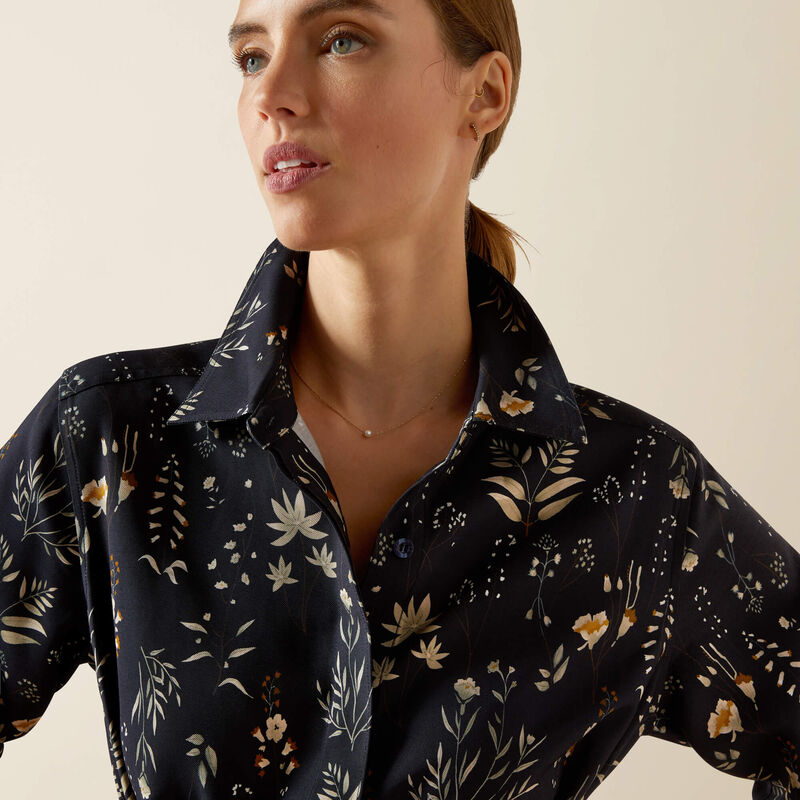 Woman wearing a dark floral patterned shirt against a beige background