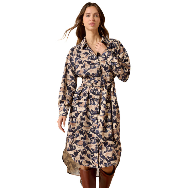 A woman modeling a long-sleeve collared shirt dress with a beige and navy blue abstract pattern, featuring a matching tie belt at the waist, set against a plain white background.