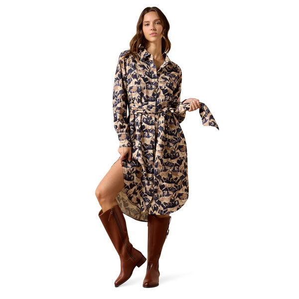 A woman models a long-sleeve belted shirt dress with a beige and navy floral pattern, paired with brown knee-high leather boots, against a solid white background.