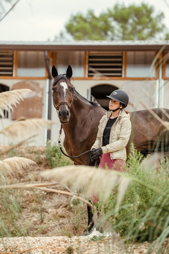 Woman standing next to a horse in an outdoor equestrian setting