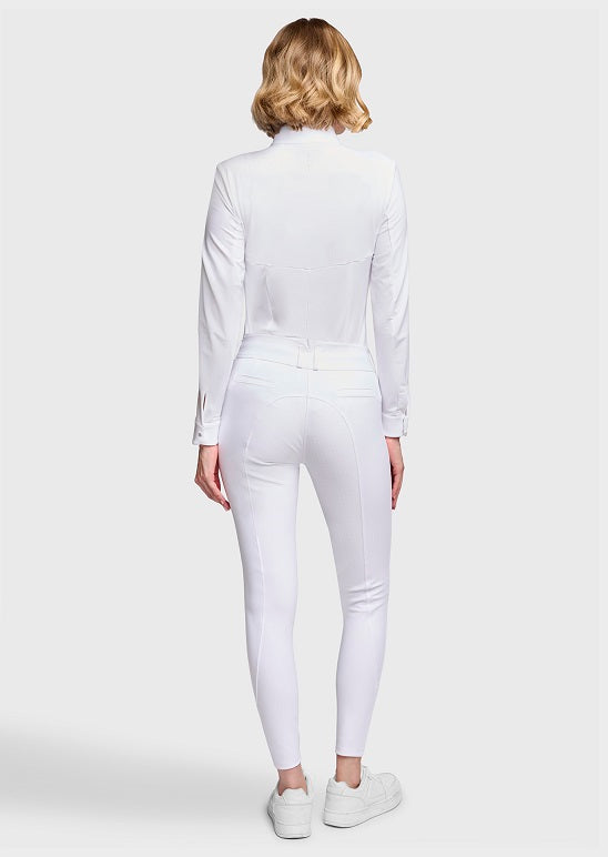 A woman viewed from the back wearing a white long-sleeve mock-neck top and matching white fitted pants, paired with white sneakers, against a light gray studio background.