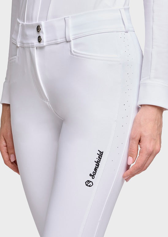 Close-up of a person wearing white equestrian riding pants with a black 'Sandsfield' logo on the left leg, shown against a light gray studio background.