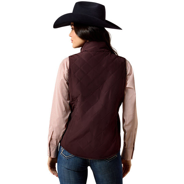 Person wearing a dark brown quilted vest over a striped shirt with a black cowboy hat on a white background