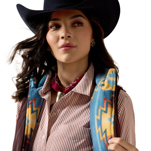 Woman wearing a cowboy hat and colorful patterned vest on a white background
