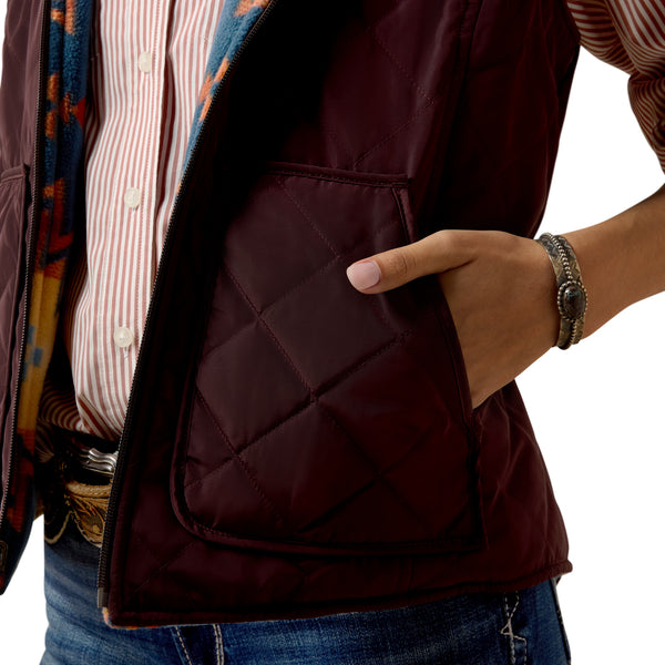 Close-up of a person wearing a dark brown quilted vest with a colorful patterned shirt underneath.