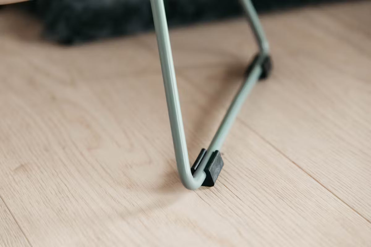 Close-up of a metal feeder leg on a wooden floor
