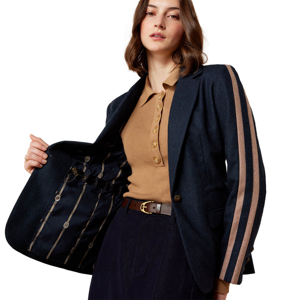 Woman wearing a navy blazer with brown accents on a white background