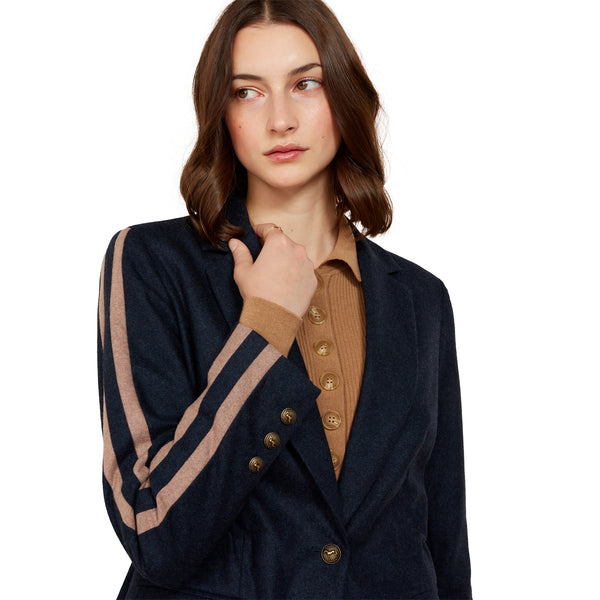 Woman wearing a navy blazer with brown accents on a white background