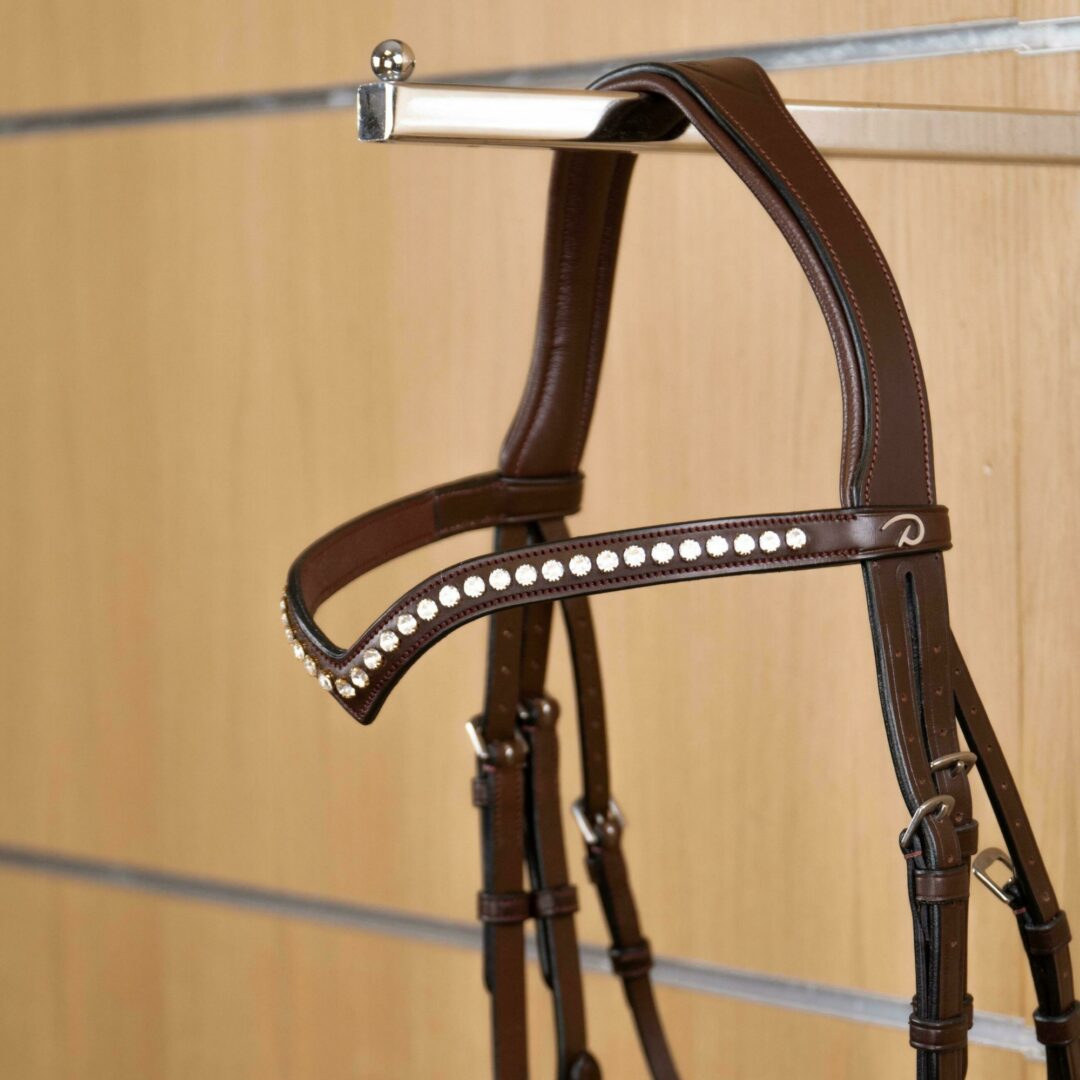 A brown V-shaped browband with white Swarovski stones, designed for horses, part of the New English collection.