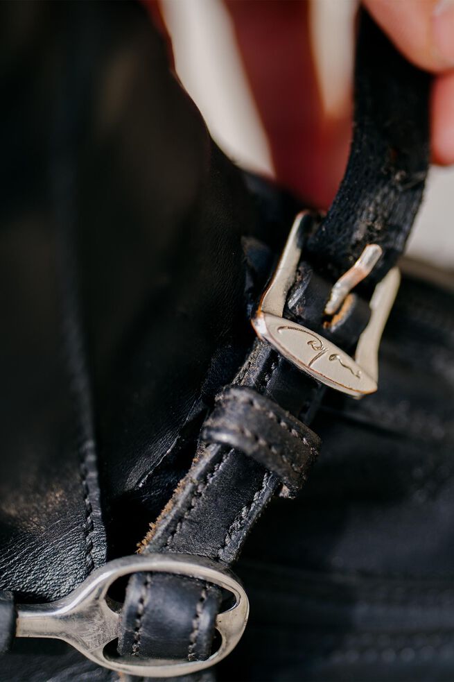 Close-up of a leather strap with metal buckles on a dark background