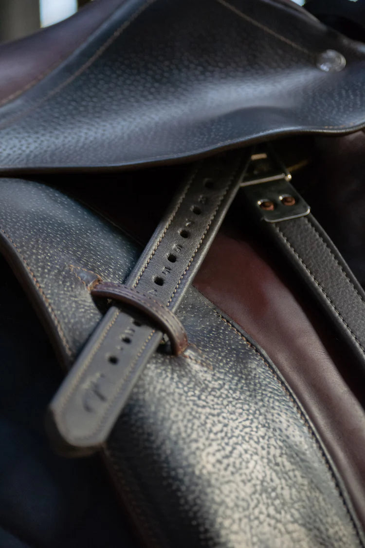 Close-up of a brown premium soft leather stirrup strap with a stainless steel buckle on a saddle.