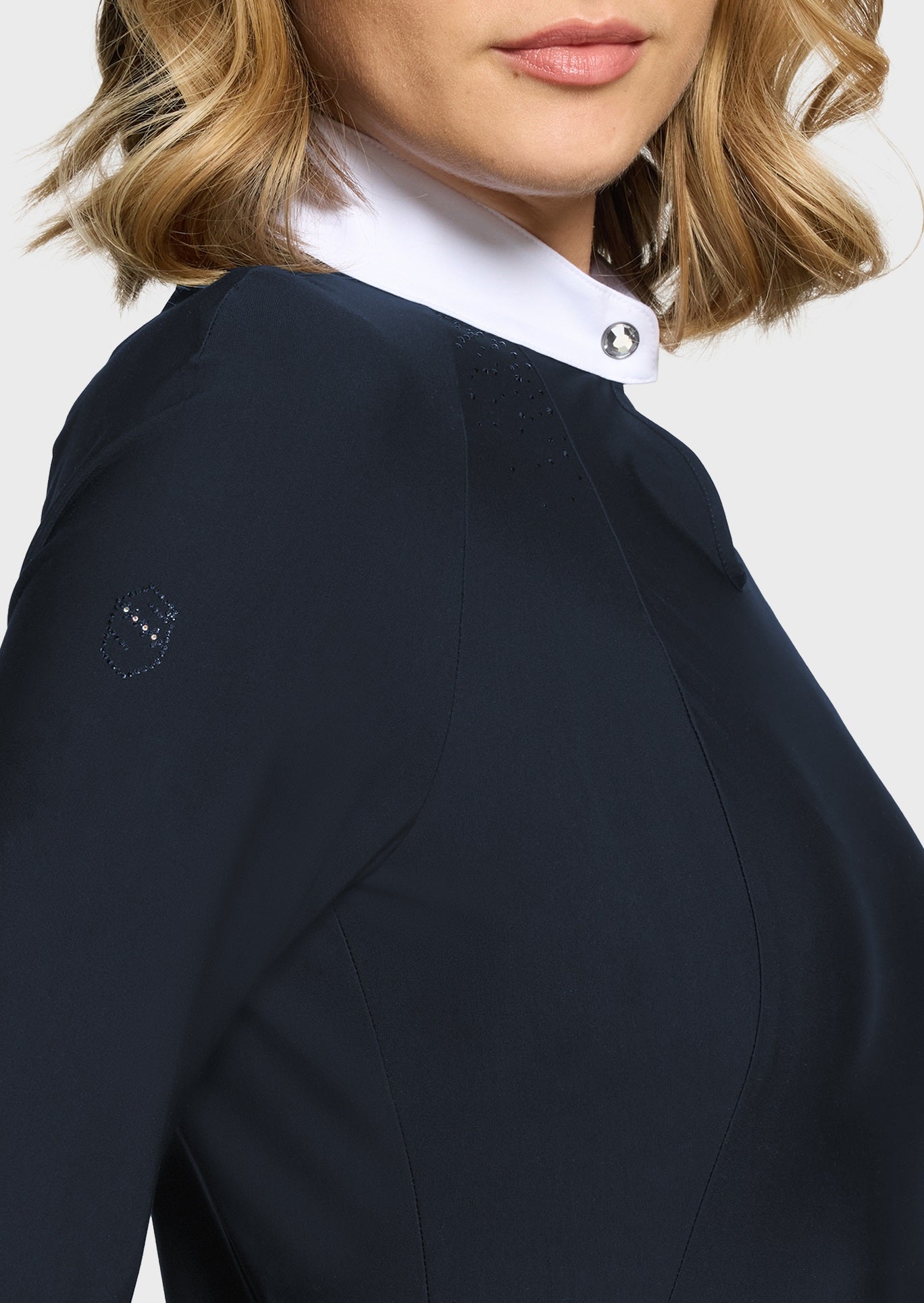 Woman wearing a navy competition shirt on a beige background
