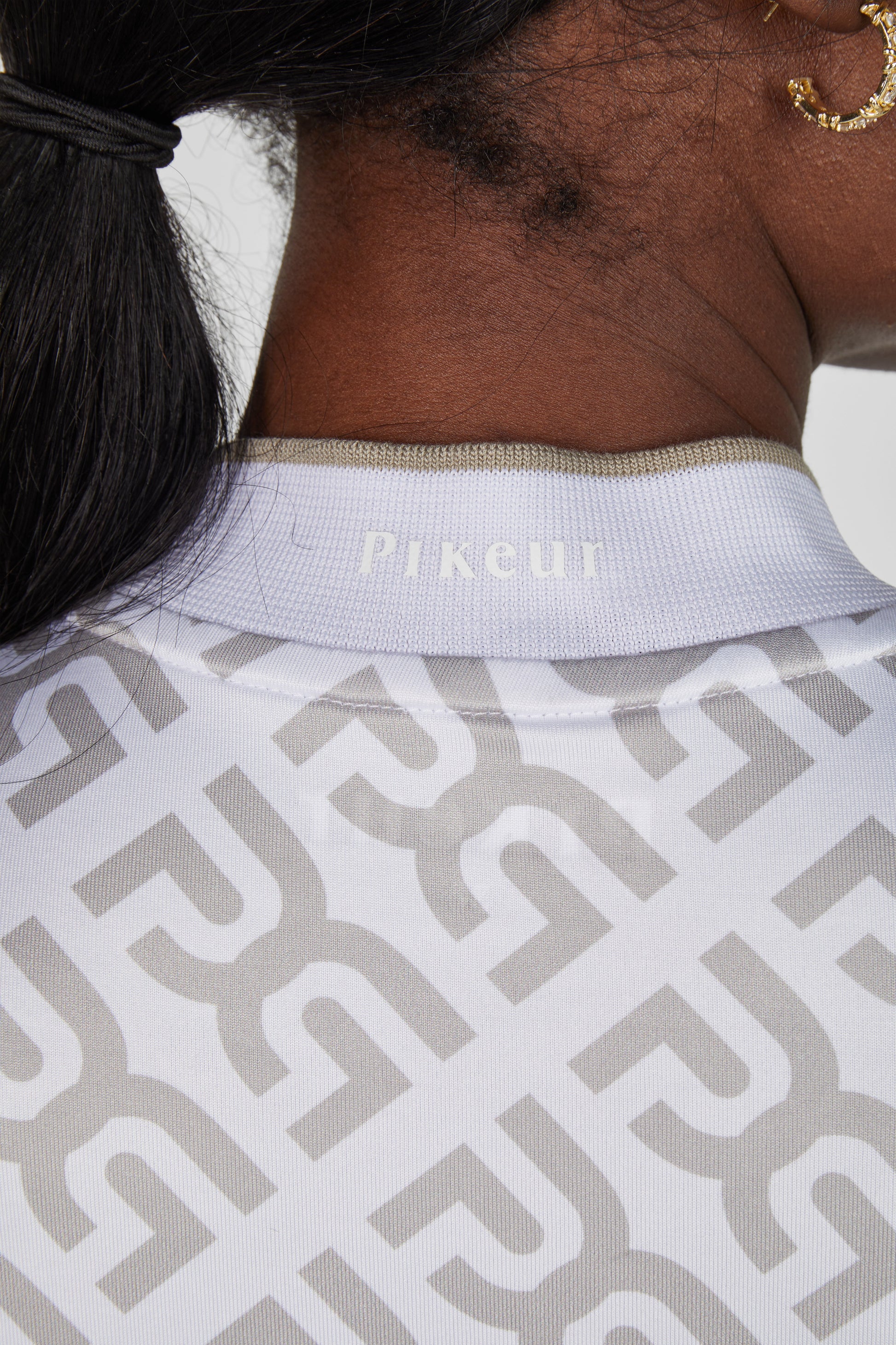 Close-up of a person wearing a Pikeur equestrian shirt with a geometric pattern.