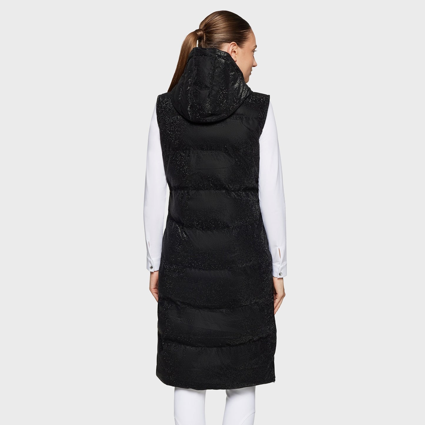 Person wearing a long black puffer vest with a hood on a white background