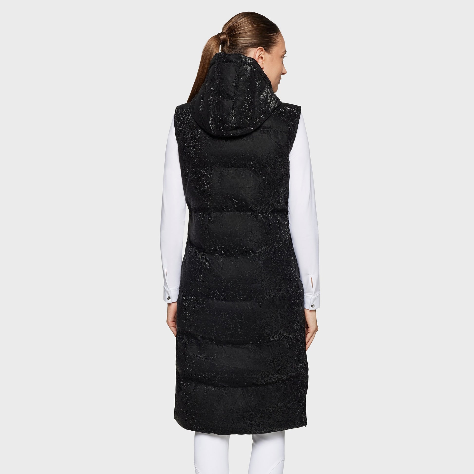 Person wearing a long black puffer vest with a hood on a white background